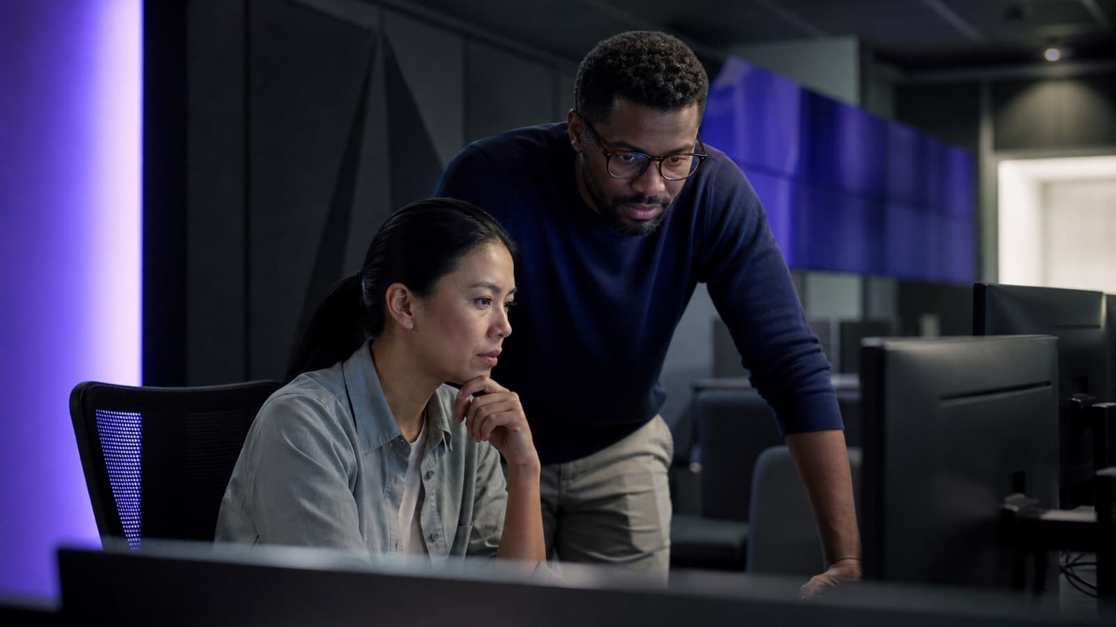 Illustrative technology scene of two operations specialists working in an unbranded control room